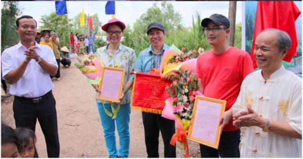 Chủ tịch UBND xã Đa Lộc (trái) và đại diện Hội đồng Họ Phạm Toàn quốc trao thư cảm ơn và cờ lưu niệm cho nhà tài trợ và KTS thiết kế cầu